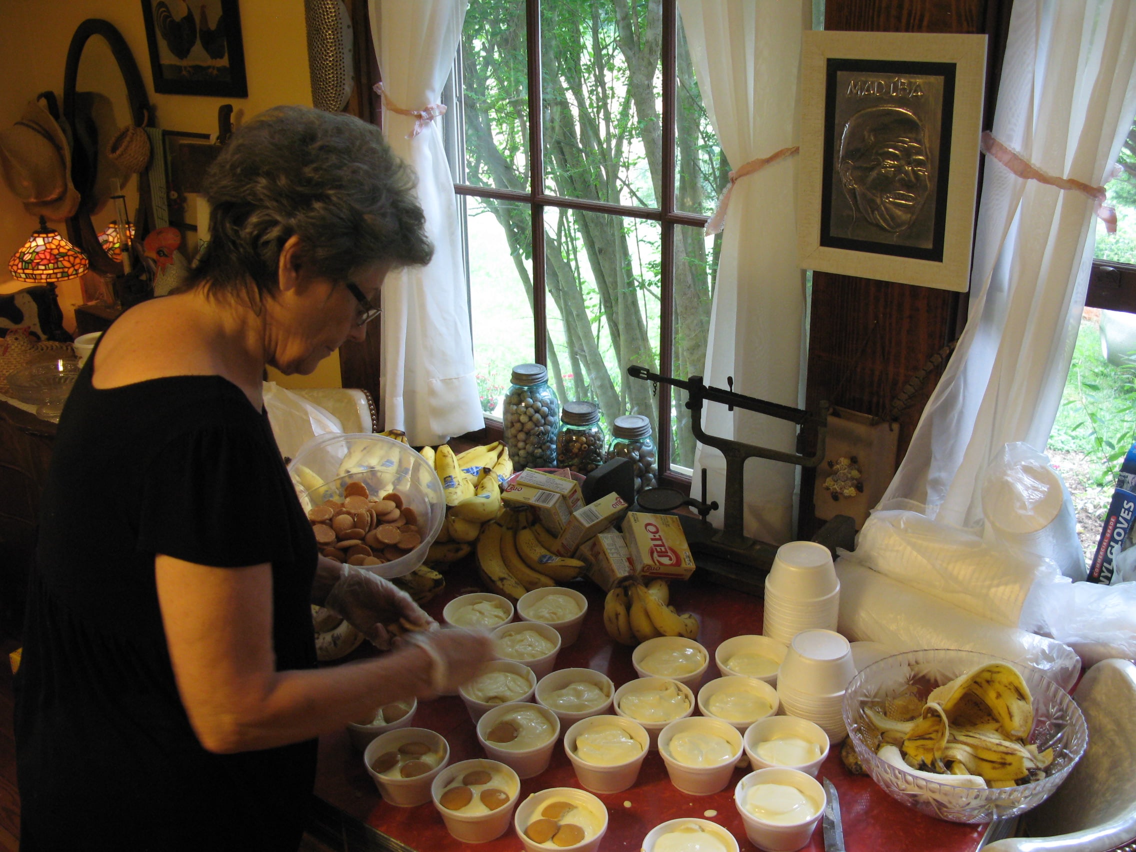 Pat placing vanilla wafers on top of the mini-puddings before putting the lids on. The relief on the wall of Nelson Mandela prompted Pat to tell the story of the time she heard him speak in Georgia in 1990. Friday, June 12, 2015. Leanne E. Smith.