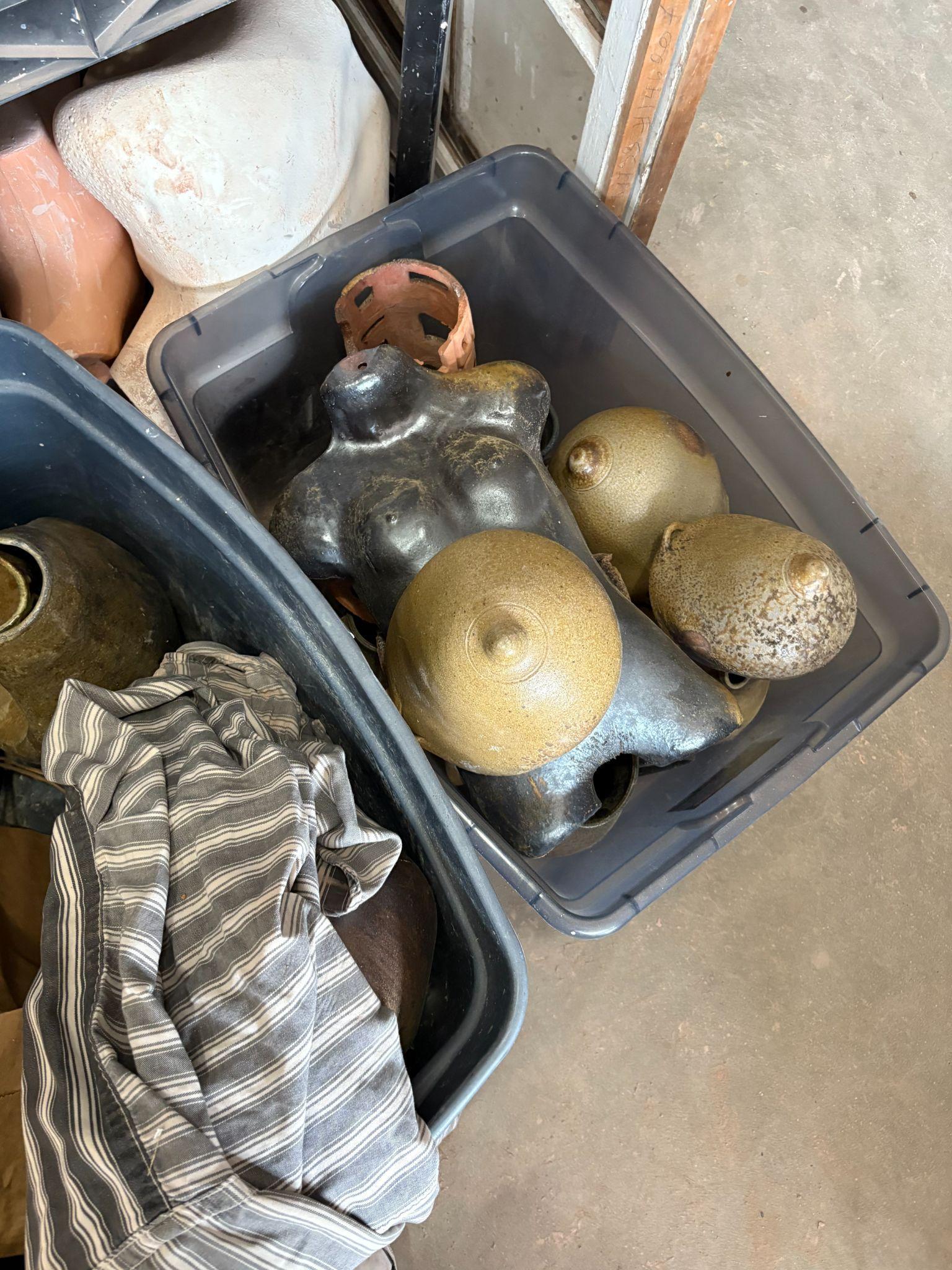 Ceramic torso forms and pottery pieces stored in a studio bin.