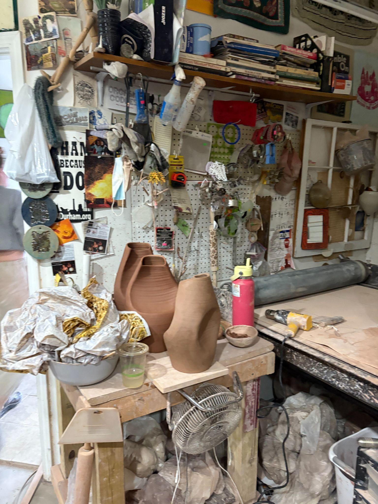 In-progress pottery forms on a table surrounded by tools in the studio.