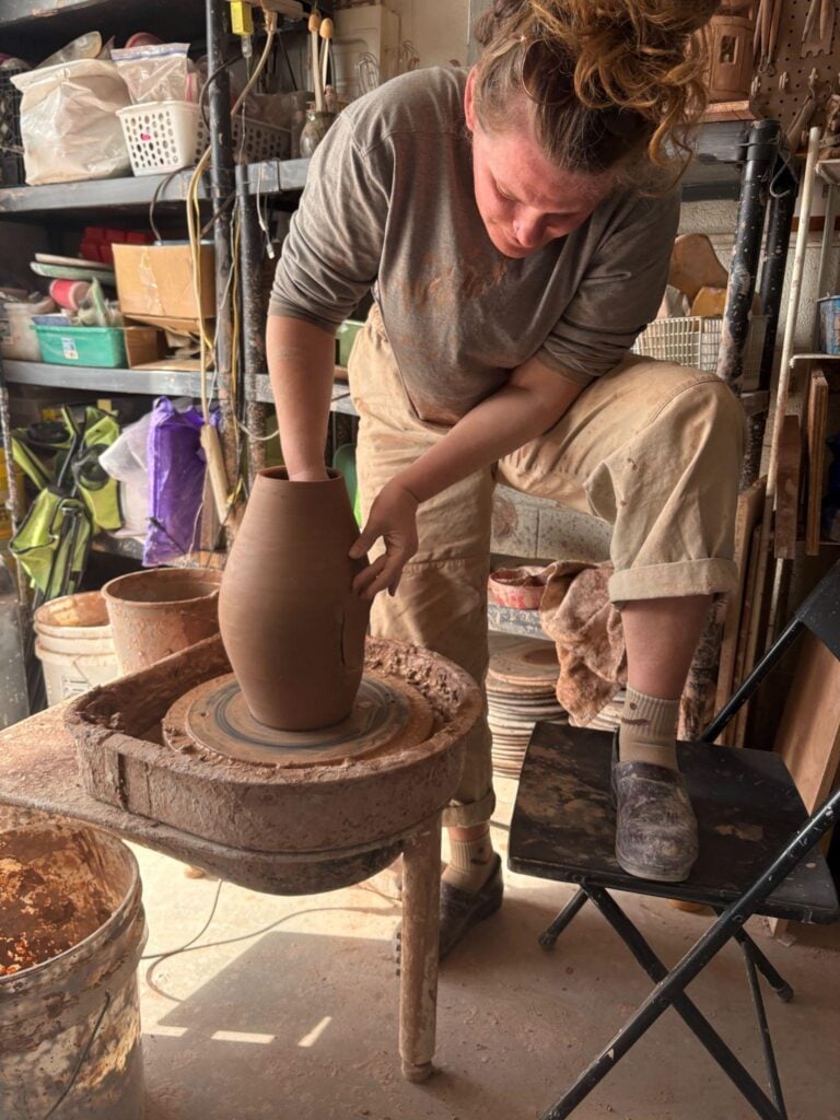 Julie Hinson shaping pottery on a wheel in her studio.