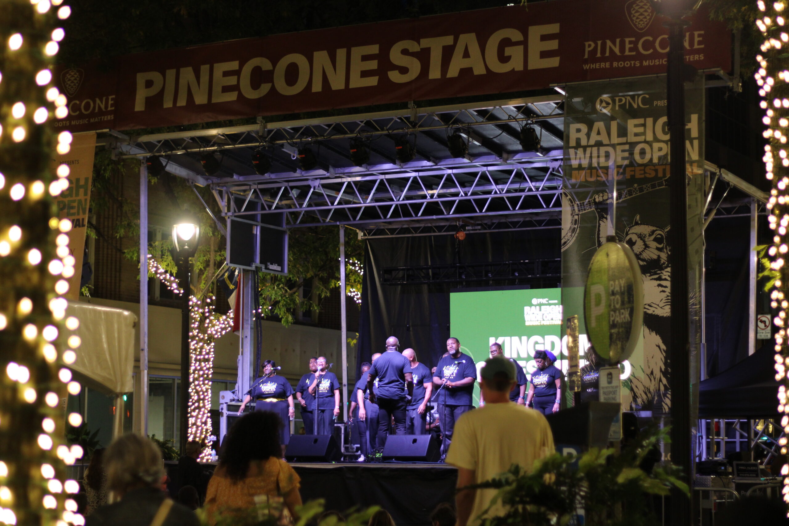 Members of the gospel group Kingdom Voices United perform on the PineCone Stage at the Raleigh Wide Open Music Festival in downtown Raleigh at night.