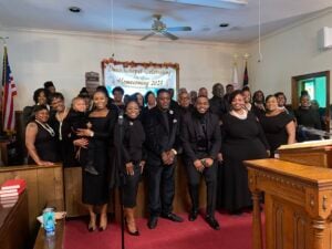 Members of Kingdom Voices United community gospel choir pose together inside a church sanctuary in Dunn, North Carolina.