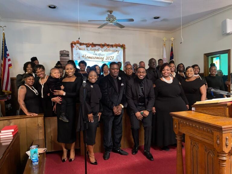 Members of Kingdom Voices United community gospel choir pose together inside a church sanctuary in Dunn, North Carolina.